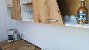 Une cuisine avec des meubles en bois, une machine à café et une grande bouteille de vin Erathia.