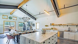 A spacious kitchen with a large island, modern appliances, and a high ceiling with exposed beams.