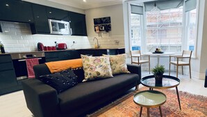 A modern living room with a black sofa, a coffee table, and a patterned rug.