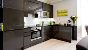 A modern kitchen with dark cabinetry, stainless steel appliances, and a white tiled backsplash.