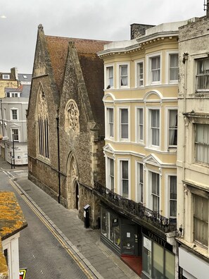 Une vue de rue avec des bâtiments historiques, dont une église à arcs brisés et un bâtiment d’angle doté de grandes baies vitrées.