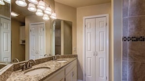 Une salle de bain avec deux lavabos, un grand miroir et une porte.