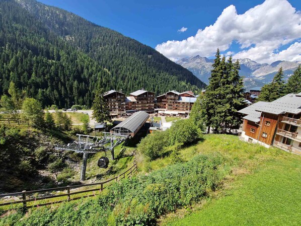 A mountain lodge with multiple buildings, a ski lift, and a forested backdrop.