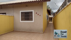 A narrow corridor with a tiled floor, a window with metal bars, and a yellow wall.