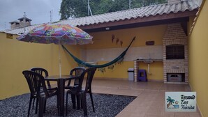 Eine Terrasse mit Tisch, Stühlen, einer Hängematte und einem Backofen aus Ziegeln.