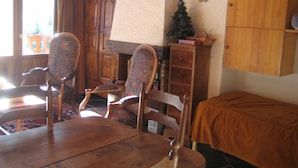 A dining area with a wooden table, two chairs, a cabinet, and a small Christmas tree.