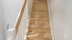 Una escalera de madera con barandillas blancas que da a una plataforma.