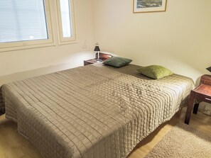 Een slaapkamer met een groot bed, een nachtkastje, een lamp en een kussen.