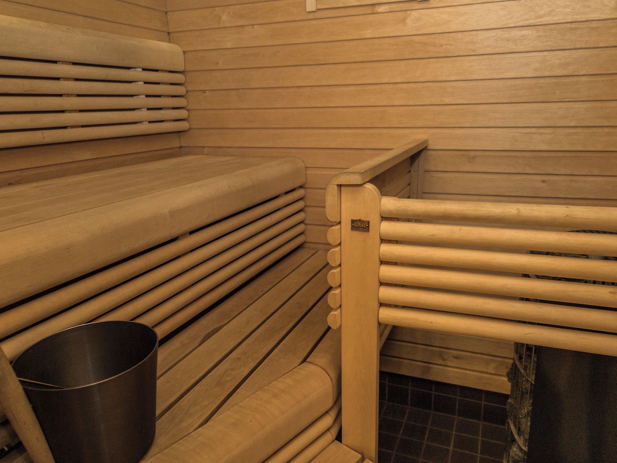Una sauna con bancos de madera y un cubo de metal.