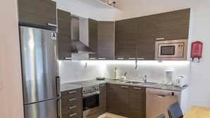 Una cocina compacta equipada con refrigerador, estufa, microondas y lavavajillas.