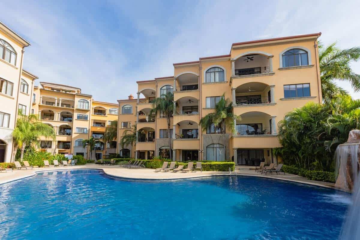 Un hôtel doté d’une piscine, de nombreux balcons et de palmiers.
