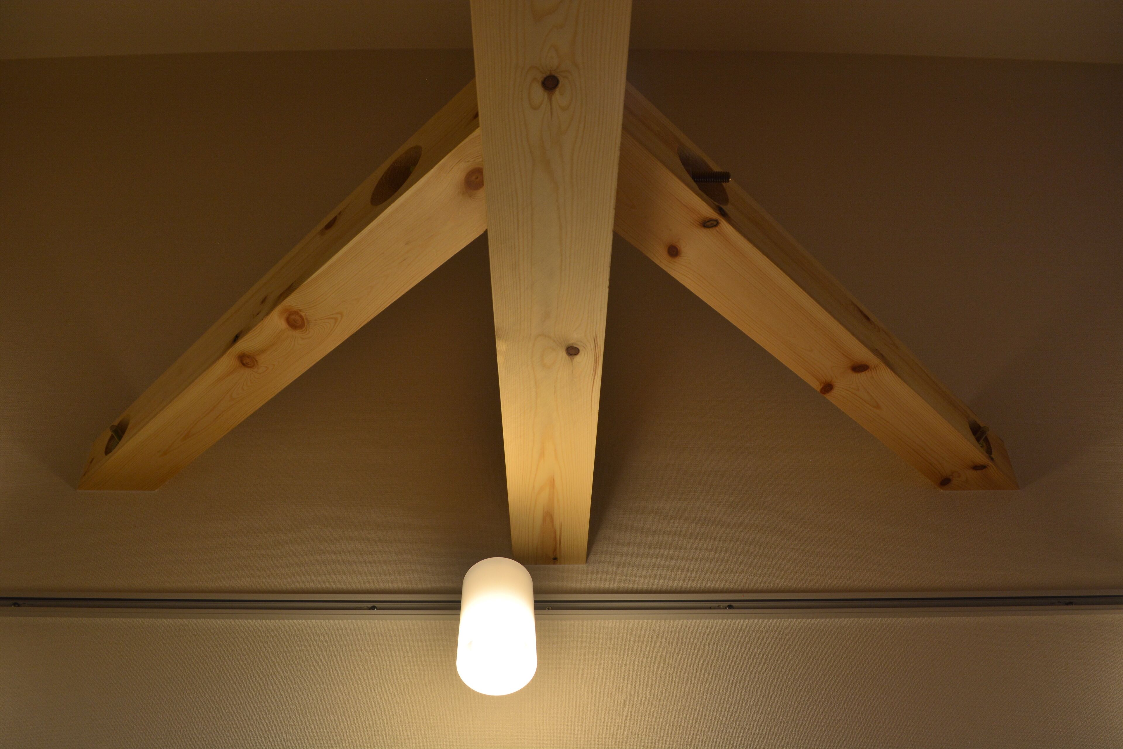 A ceiling with wooden beams and a single light fixture.