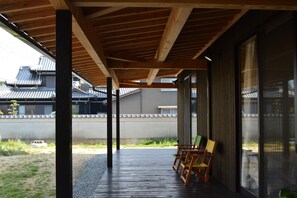 A covered outdoor area with wooden beams and a view of traditional buildings in the background. - BED N CHILL Shippoya - Hostel (Mitoyo)