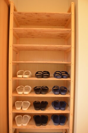 A wooden shoe rack with multiple shelves holding pairs of shoes. - BED N CHILL Shippoya - Hostel (Mitoyo)