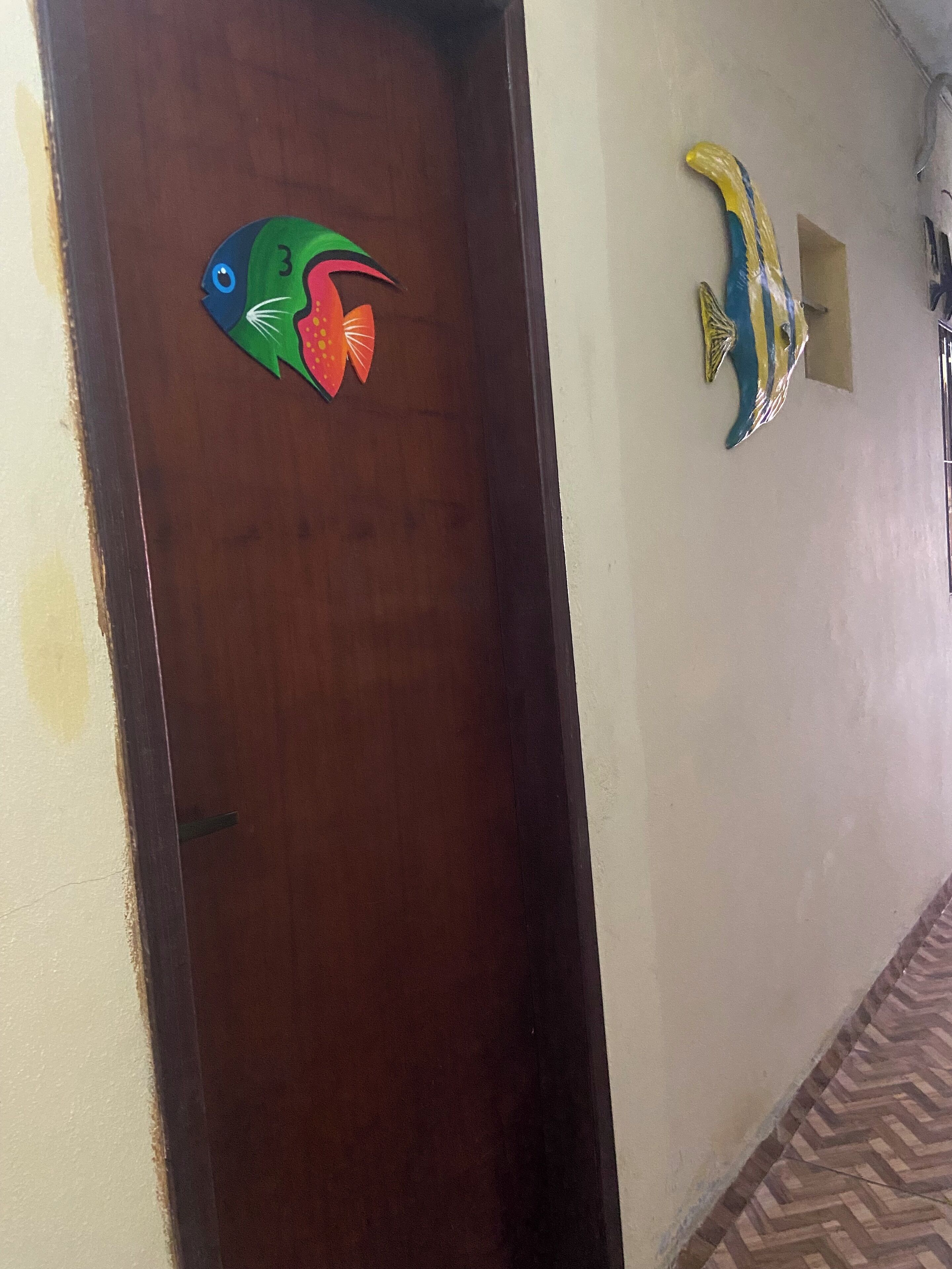 Una puerta de madera con una decoración de pez colorido y un adorno de pez en la pared.