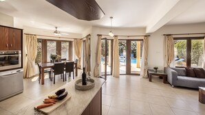 A spacious living area with a kitchen, dining table, and a sofa. - Villa Tsikkos Dio: Beachfront, Pool, A/C, WiFi (Argaka)