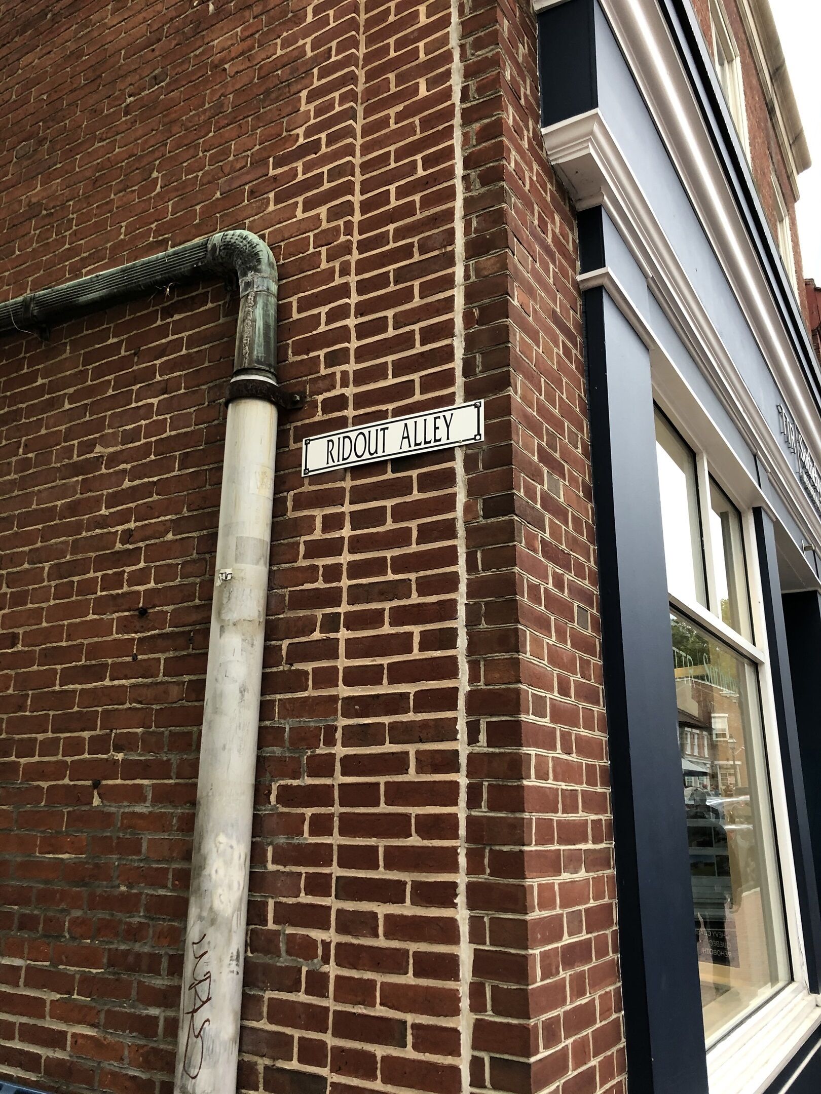 Um edifício de tijolos com uma placa de rua que diz 'RIDOUT ALLEY'.