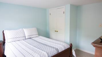 Een slaapkamer met een bed, een houten nachtkastje en een witte deur.