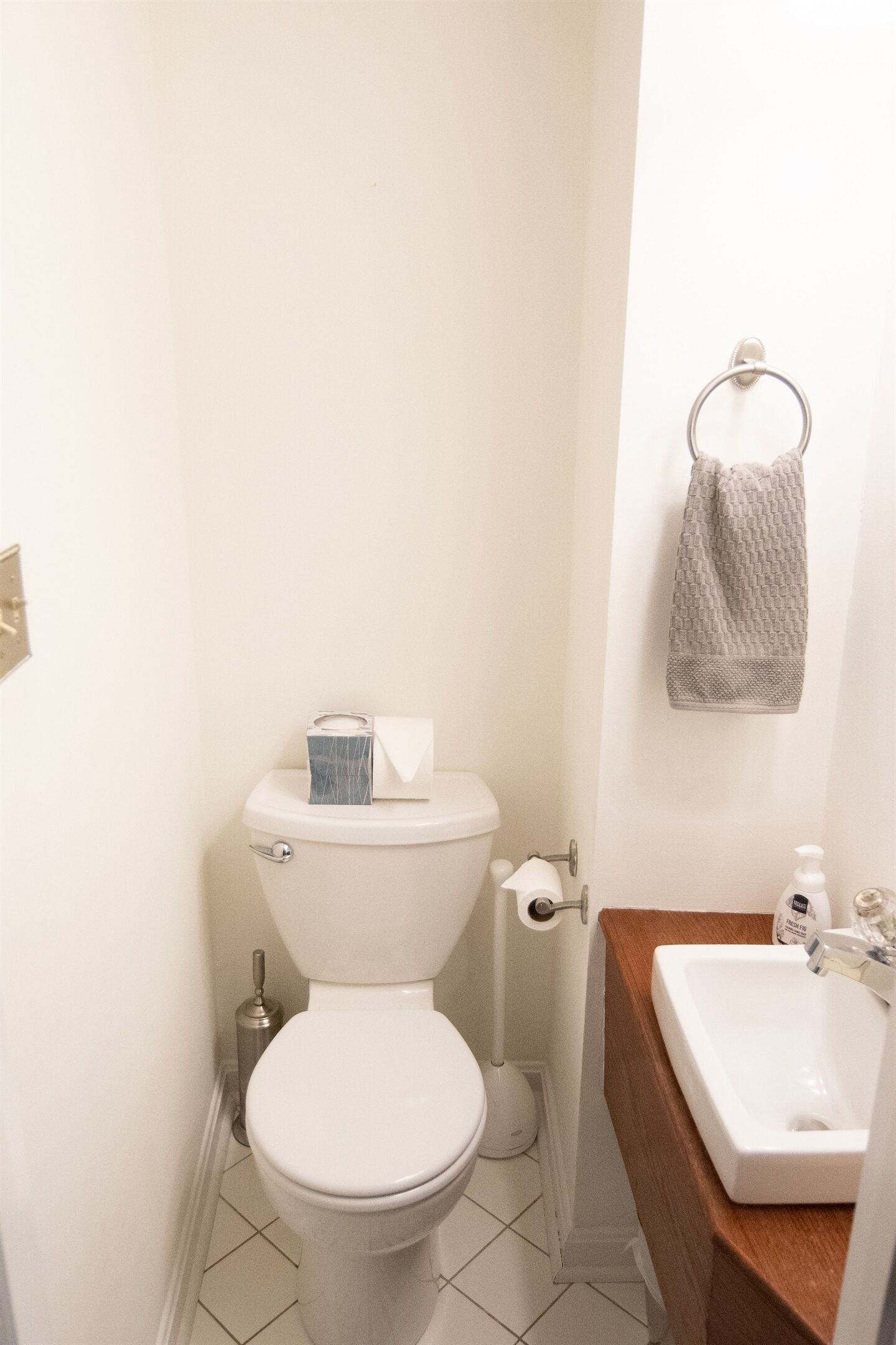 A small bathroom with a toilet, a sink, and a towel hanging on the wall.