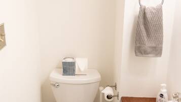 A small bathroom with a toilet, a sink, and a towel hanging on the wall.