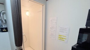 A room with a shower, a small wooden bench, a black cabinet, and a wall with informational notices. - Hotel El Shinjuku 2 (Tokyo)