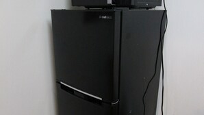 A black refrigerator with a microwave on top, connected to a power strip on the floor. - Hotel El Shinjuku 2 (Tokyo)