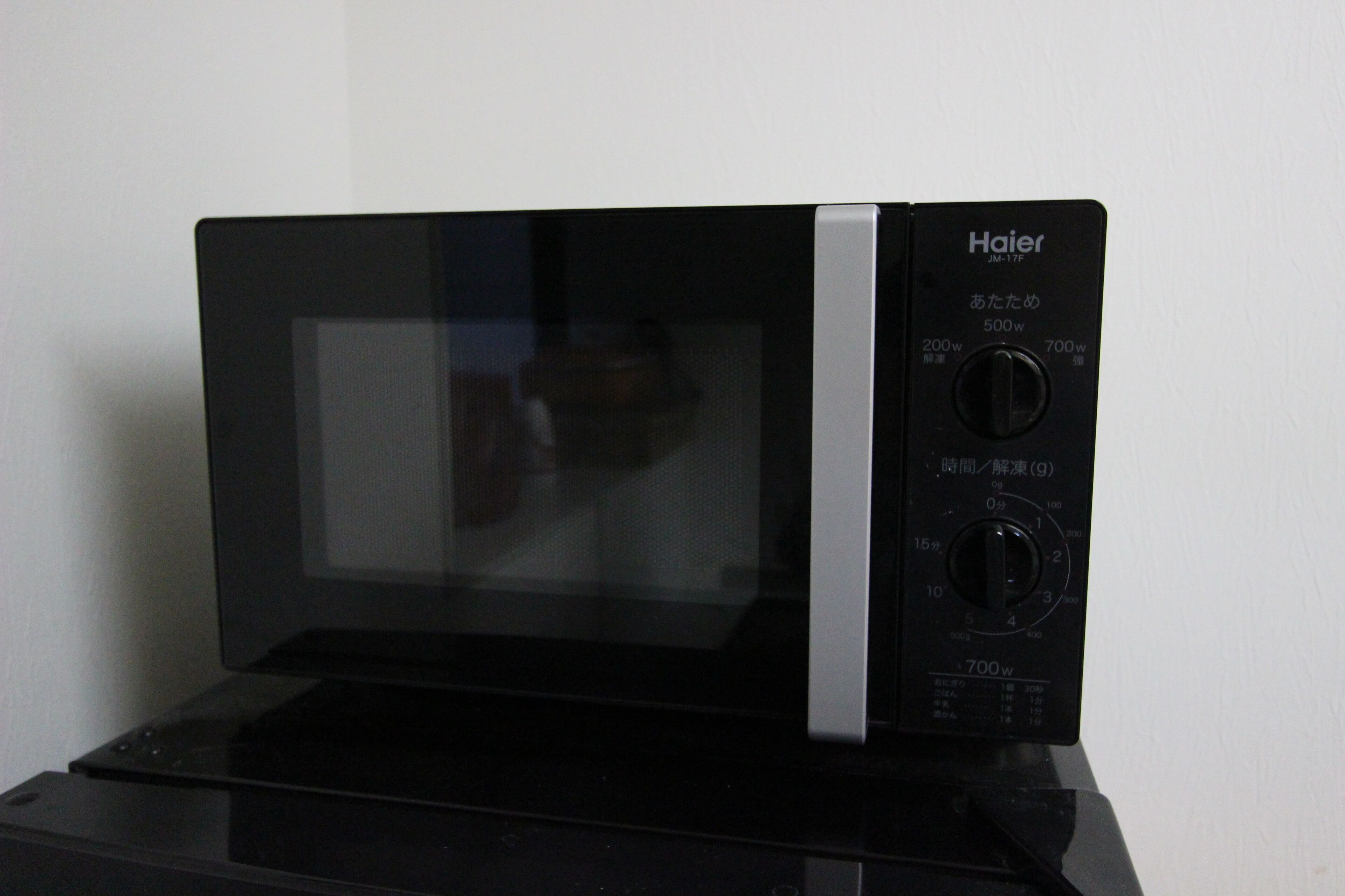A black Haier microwave oven with two control knobs and a digital display, placed on a black surface.