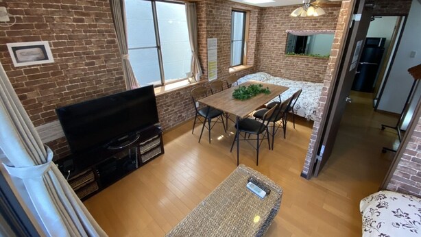 A compact living space with a dining area, a television, and a kitchen visible through an open doorway. - Hotel El Shinjuku 2 (Tokyo)