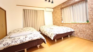 A room with two beds, a brick wall, and a window with curtains. - Hotel El Shinjuku 2 (Tokyo)