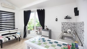 A modern kitchen with a tiled backsplash, a sink, and a dining area with a striped sofa and a teddy bear. - Ciel Pension (Yangyang)