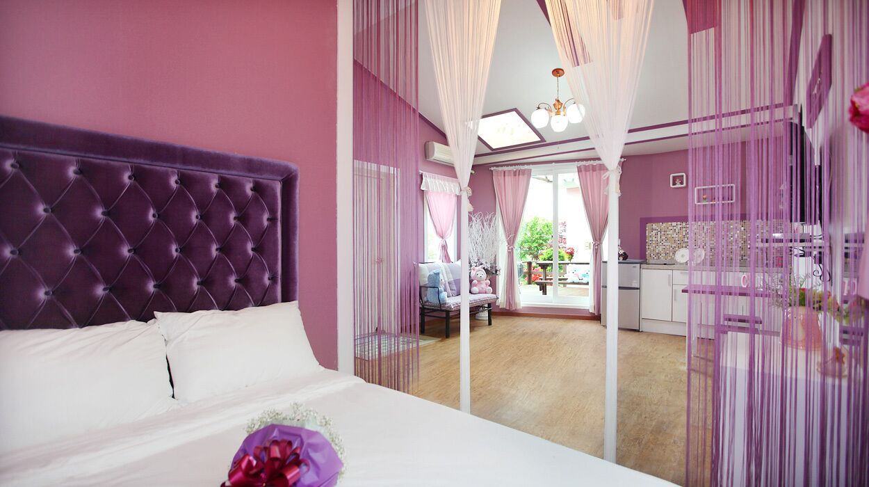 A bedroom with a tufted headboard, a bed with white linens, and a bouquet of flowers.