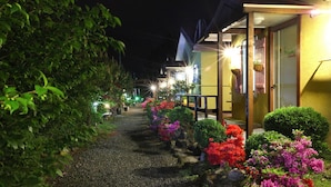 A pathway lined with colorful flowers leading to a building with a yellow exterior and a visible entrance door. - Ciel Pension (Yangyang)