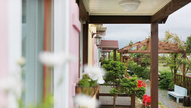 A covered outdoor area with a wooden pergola, a bench, and potted plants. - Ciel Pension (Yangyang)