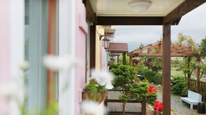 A covered outdoor area with a wooden pergola, a bench, and potted plants. - Ciel Pension (Yangyang)
