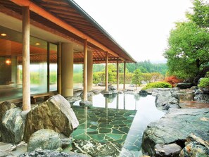 A traditional Japanese-style building with a covered outdoor area featuring a stone-tiled pool surrounded by rocks. - Kamedake Onsen Tamaminesansou (Okuizumo)