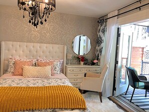Una camera da letto con testiera trapuntata, un letto con biancheria a motivi, una cassettiera, uno specchio e vista sull'esterno tramite una porta scorrevole.