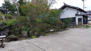 A traditional Japanese building with a stone pathway leading to a wooden bench. - Resort House FURUSATO (Nozawaonsen)