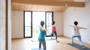 A yoga class in a room with wooden floors and large windows. - Ananda Chillage (Yakushima)