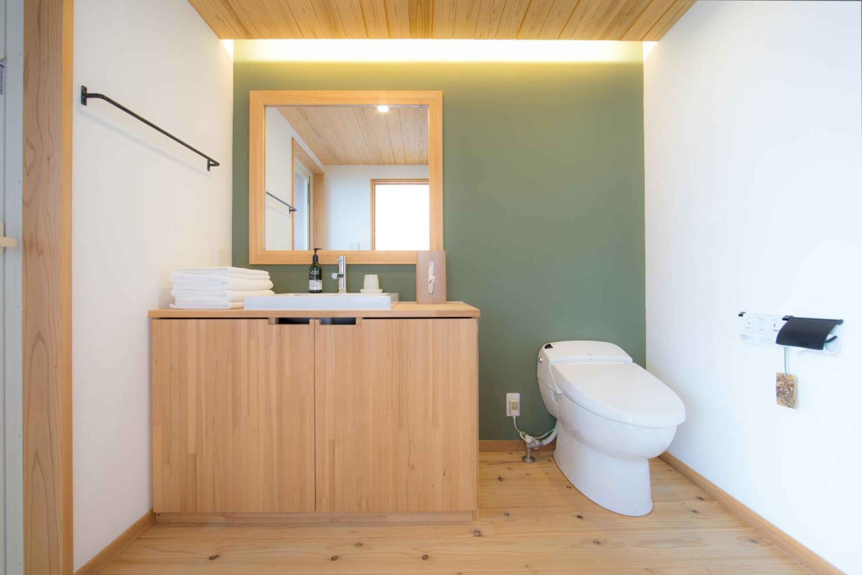 A small bathroom with a wooden vanity, a white toilet, and a mirror above the sink.