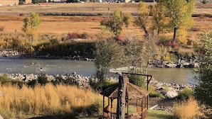 A riverside view with a gazebo, a river, and a mountainous backdrop.