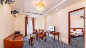A hotel room with a sofa, a desk with a computer, a bed, and a chandelier. - AD 41 Hotel (Hue)