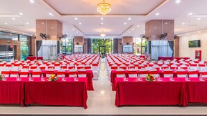 A conference room with rows of tables, each with a red tablecloth and white chairs. - AD 41 Hotel (Hue)