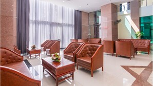 A lobby with leather sofas, wooden tables, and a large window with curtains. - AD 41 Hotel (Hue)