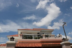 A modern house with a red-tiled roof, white walls, and a balcony.