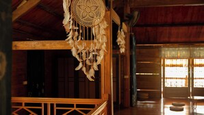 Un interior de madera con una decoración colgante tejida de estilo tradicional, una barandilla de madera y vistas a una puerta de madera.