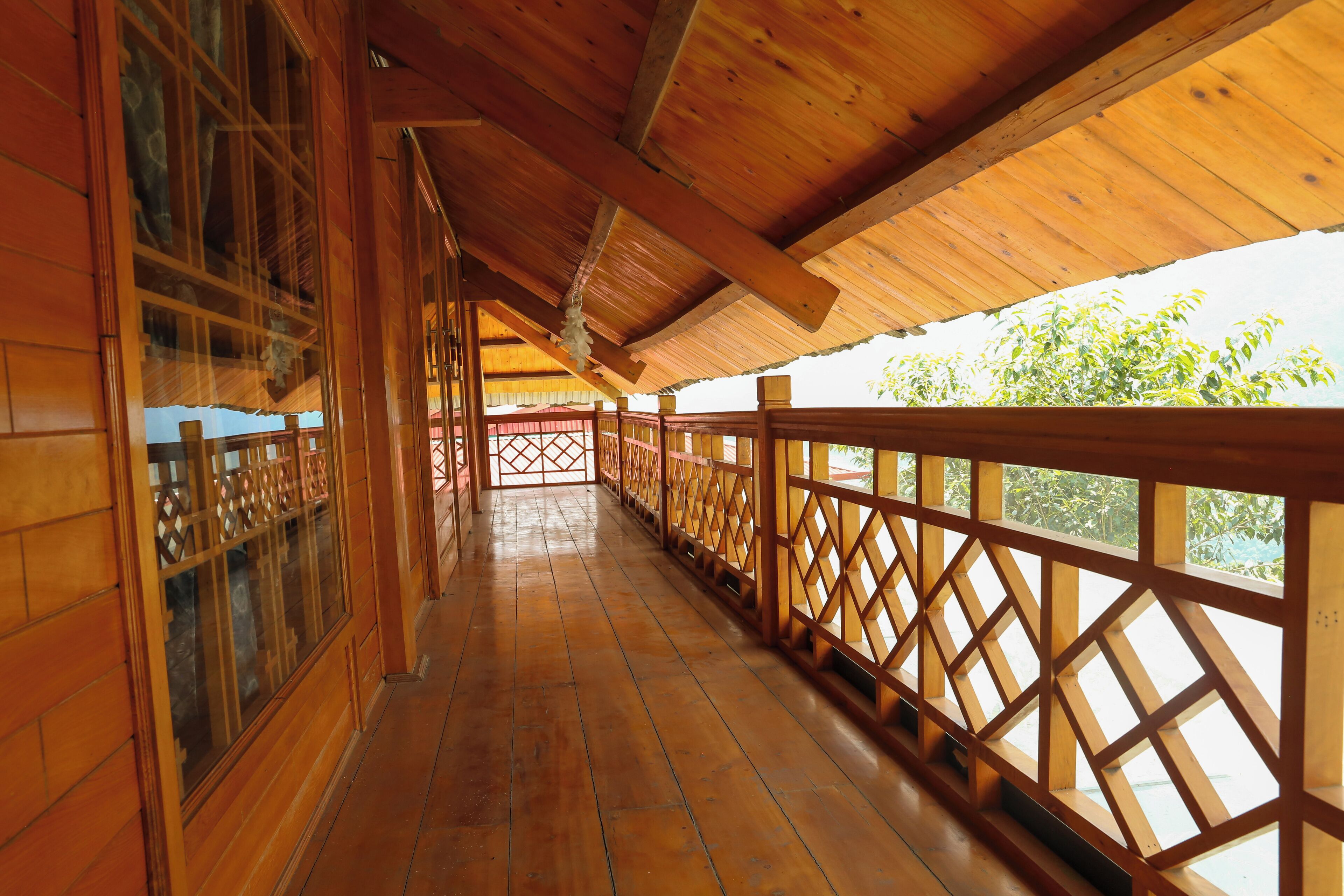 A wooden corridor with a wooden railing and a view of trees.