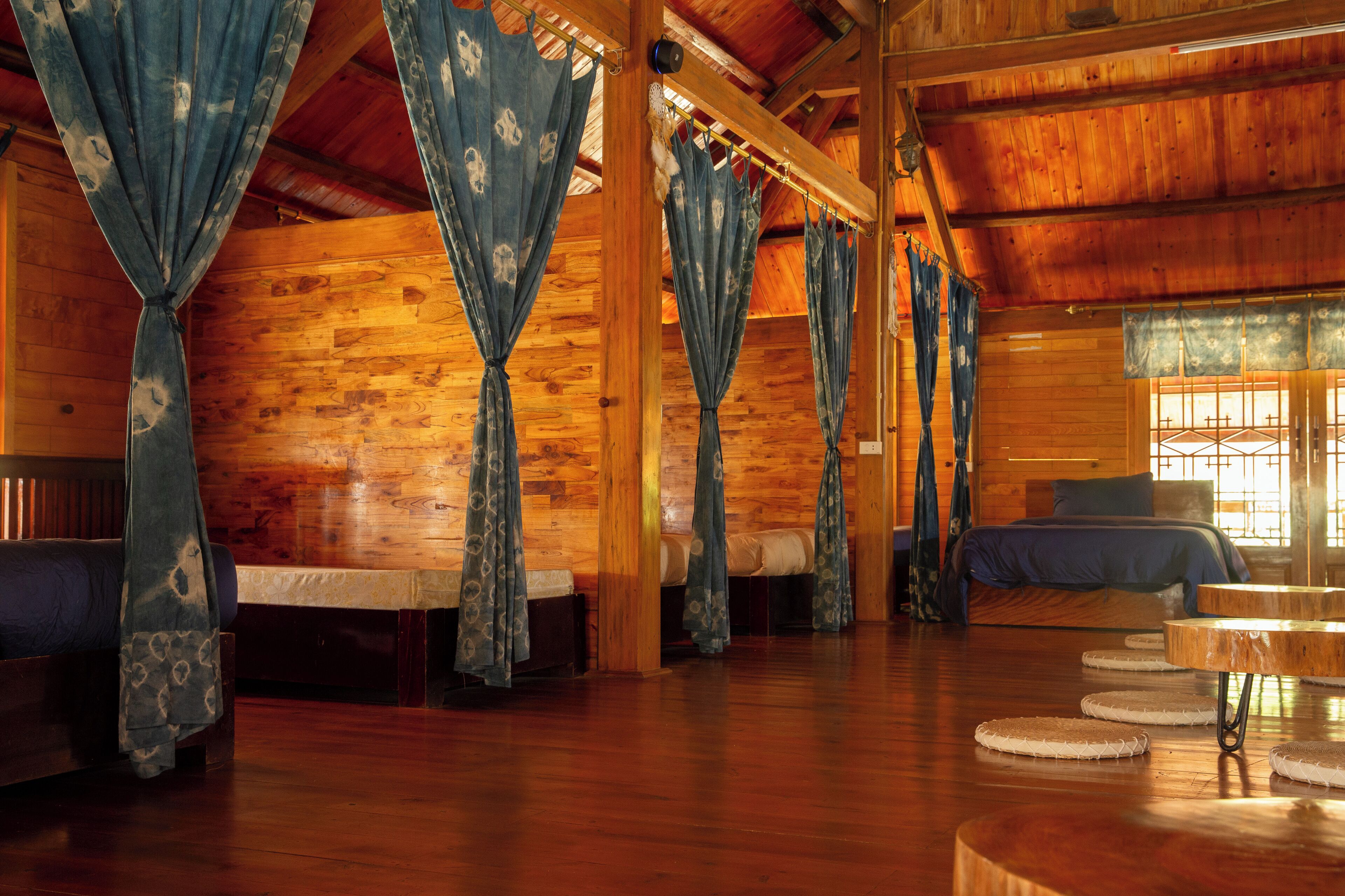 A wooden cabin interior with a bed, a sofa, and a round wooden table.