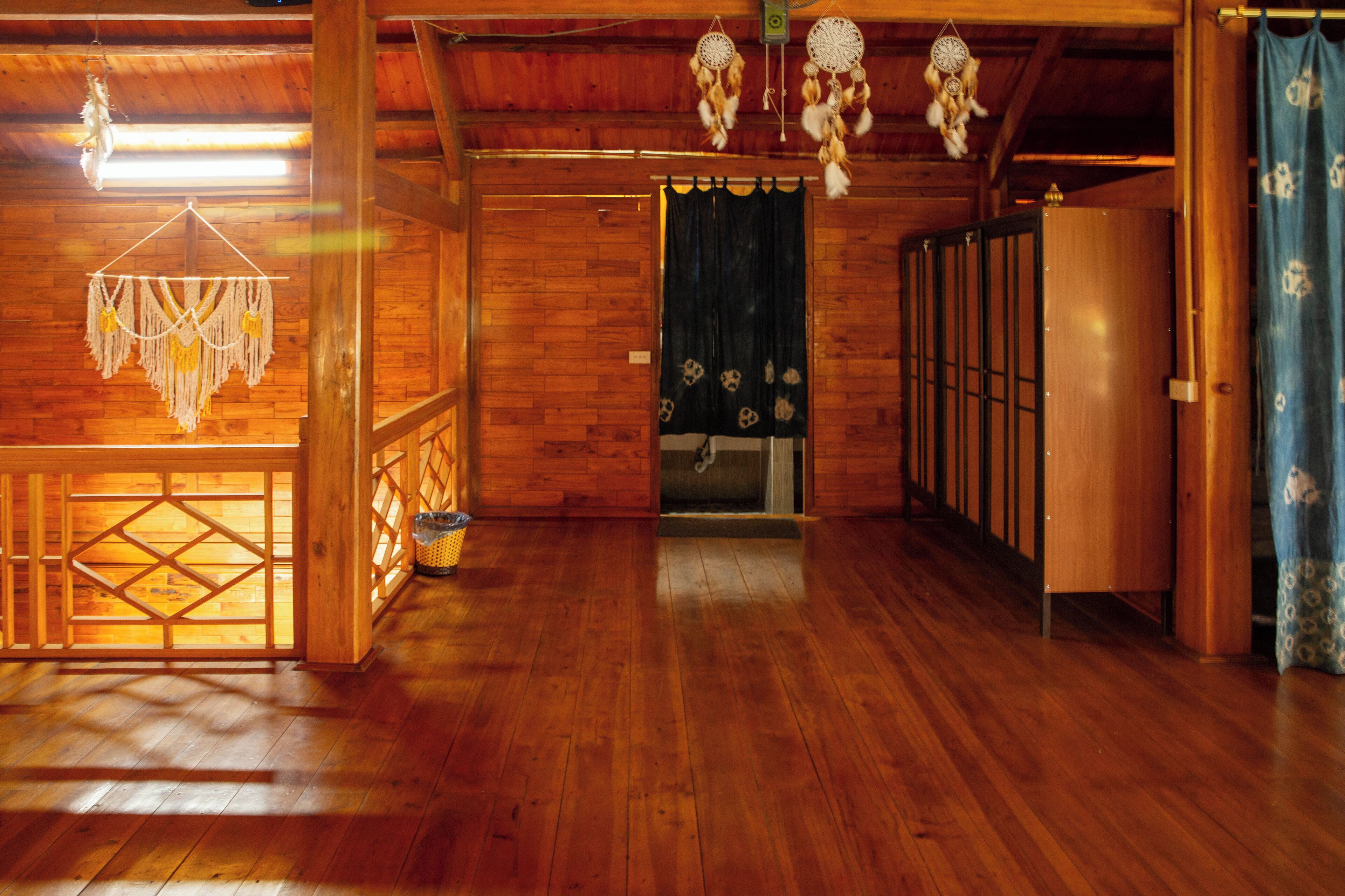 A wooden interior with a wooden floor, a doorway with a curtain, and a hanging dreamcatcher.
