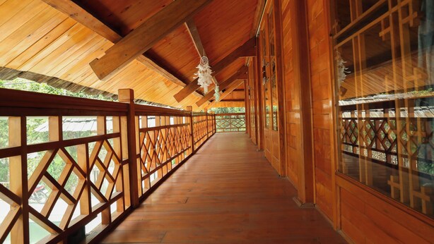 Un pasillo de madera con techo y paredes de madera, que conduce a una puerta de vidrio.