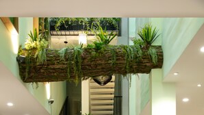 A spacious lobby with a central seating area featuring wicker chairs with teal cushions, surrounded by large potted plants and a hanging green wall. - Dai Nam Sai Gon Hotel (Ho Chi Minh City)